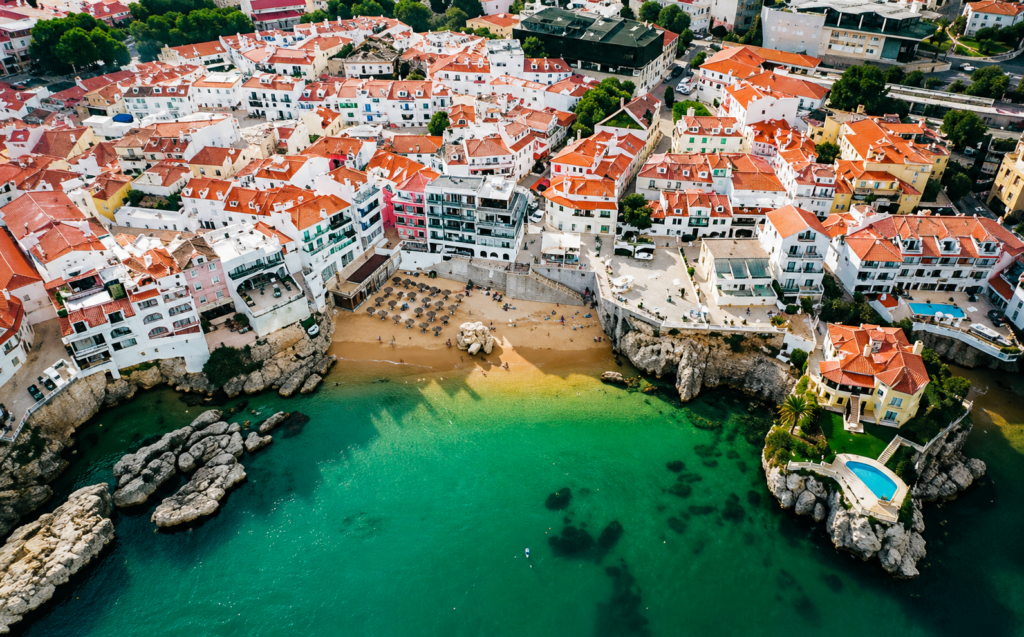 Aerial view of Cascais on the Portuguese Riviera with old town, red roofs, rocky coast, beach and turquoise Atlantic Ocean – a destination for private flights from Switzerland.